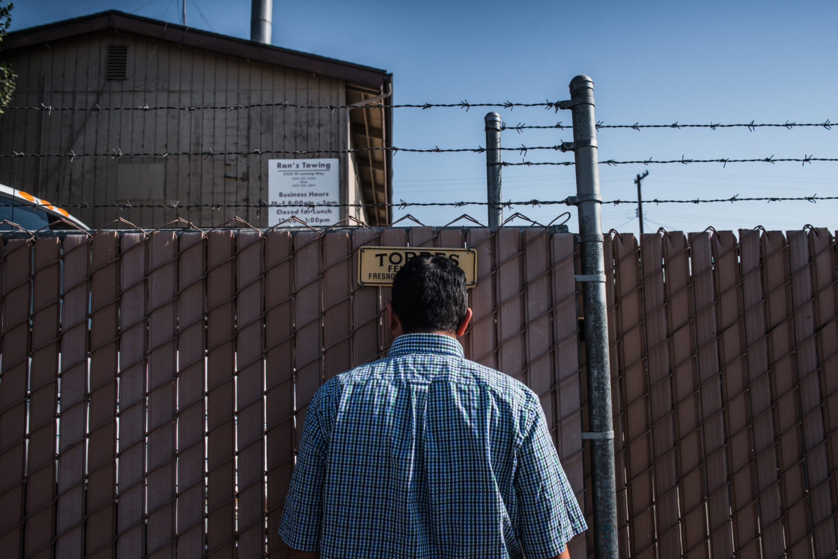 Vinson Fernandez waits outside of a tow-yard to pick up his totaled car.